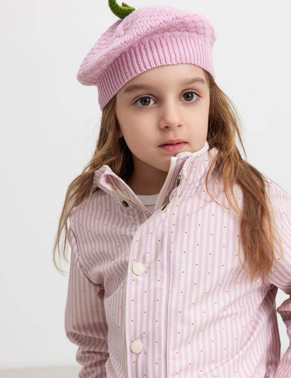 Barn iført lyserød strikket hue og stribet regnjakke