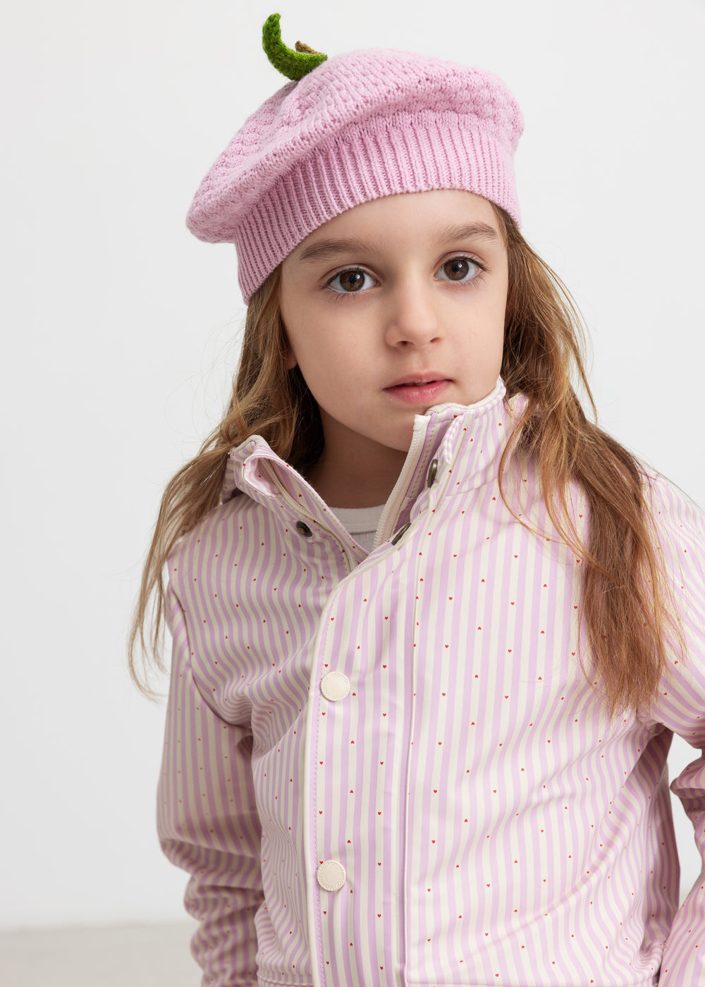 Barn iført lyserød stribet regnjakke og matchende hue