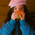 Barn i blå termo jakke med blomstret print og lyserød strikket hue 