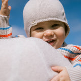 Baby iført strikket hue og stribet bluse