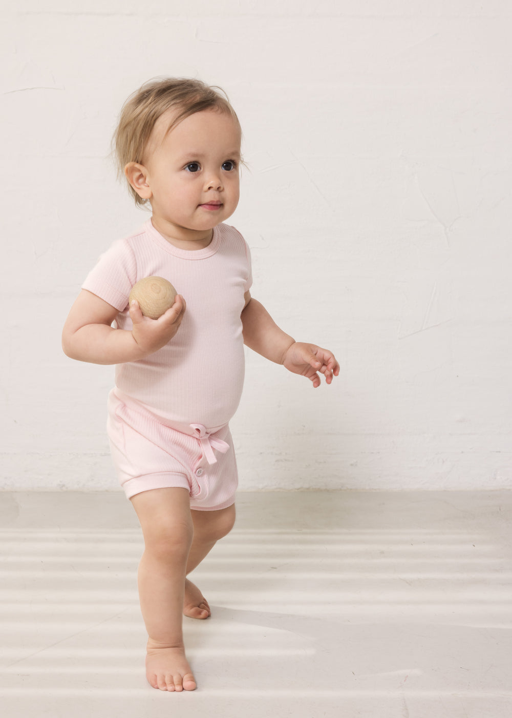 Baby iført Lyserød kortærmet baby bodystocking og bloomers