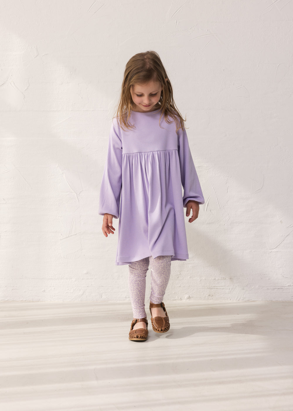 Pige iført lilla langærmet ribstrikket kjole