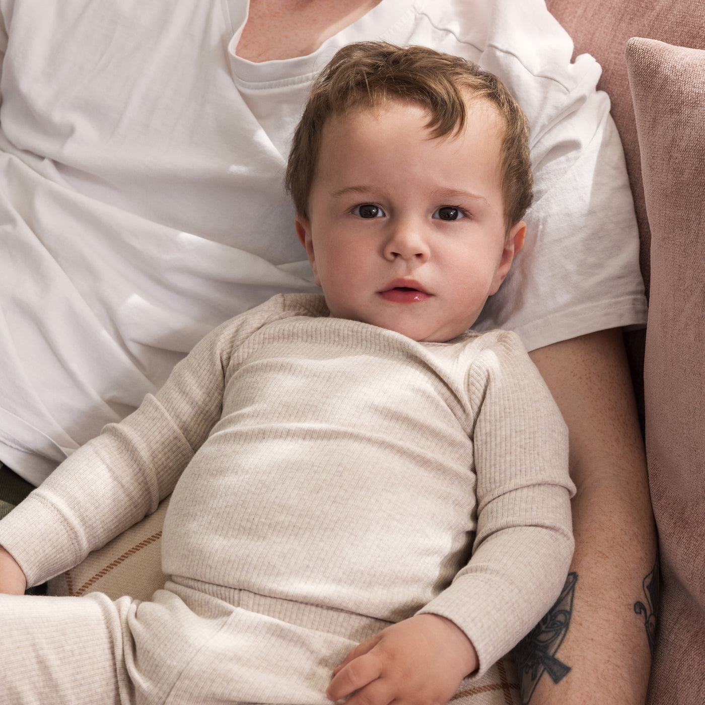 Baby i beige body og leggings, som sidder hos sin far