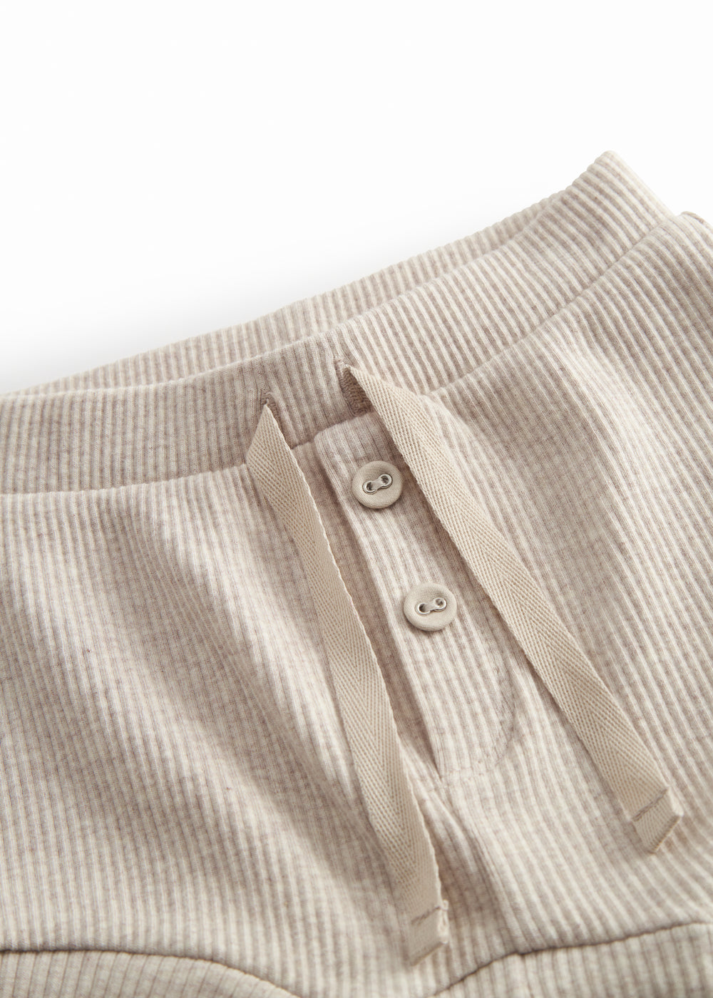 Beige baby bloomers med stolpe knaplukning og et pyntebånd i livet