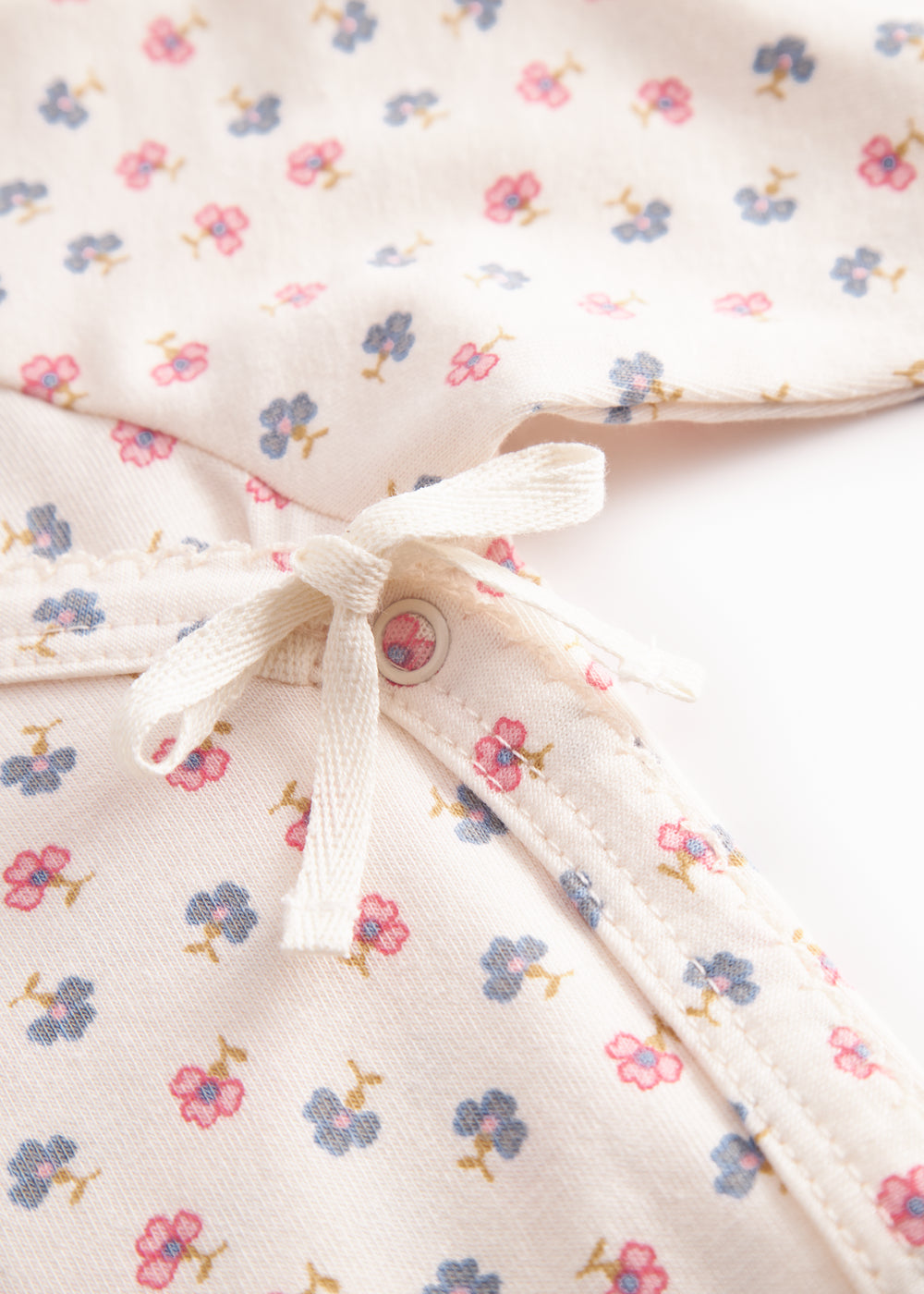 Langærmet bodystocking til nyfødt baby med slå-om-lukning og blomster