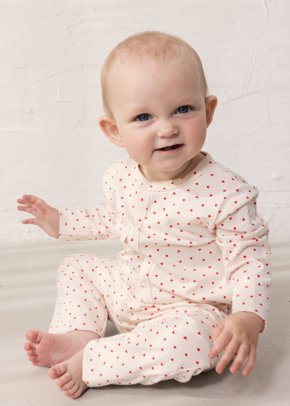 baby iført heldragt med et sødt hjerte print og med trykknaplukning hele vejen