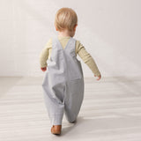 Barn iført grønstribet body under grå overalls