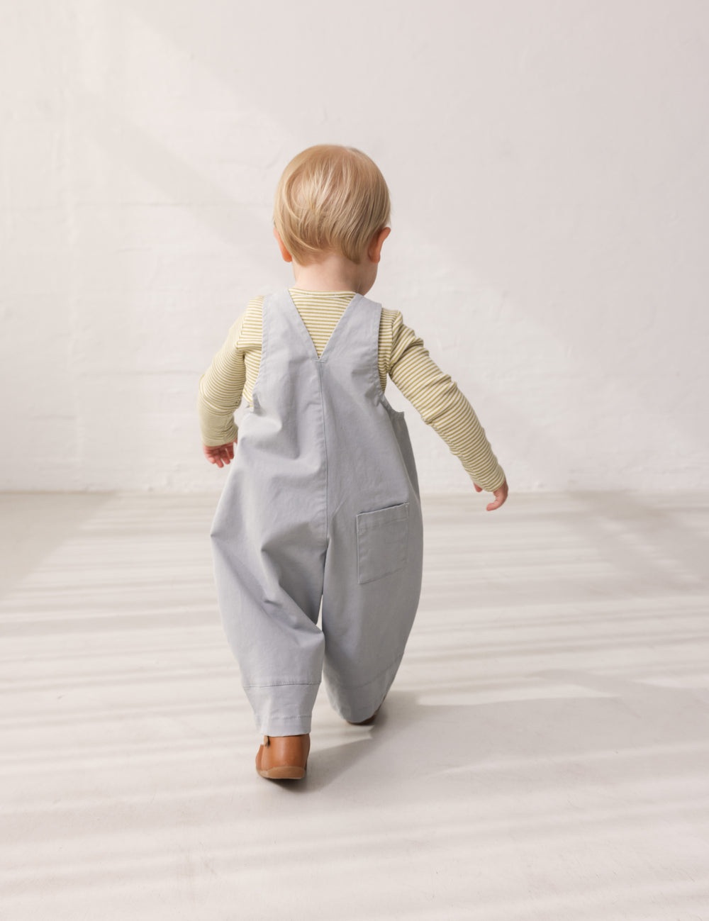 Baby iført lyseblå chino selebukser og grøn body