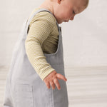 Barn iført grønstribet body under grå overalls