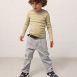 Barn iført grønstribet langærmet bluse og lyseblå chino bukser