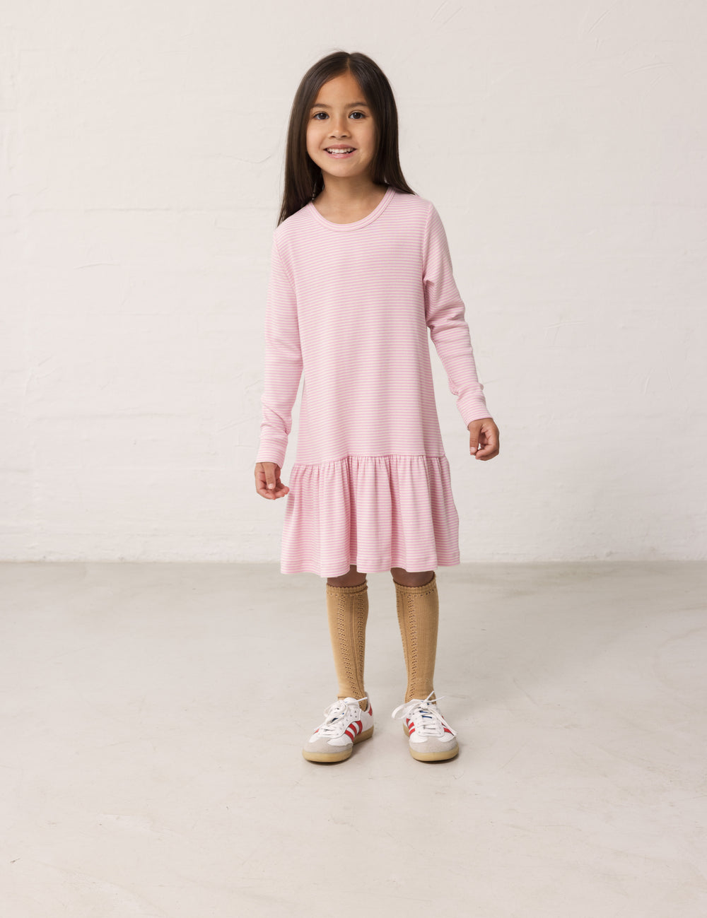 Barn iført lyserødstribet kjole med lange ærmer