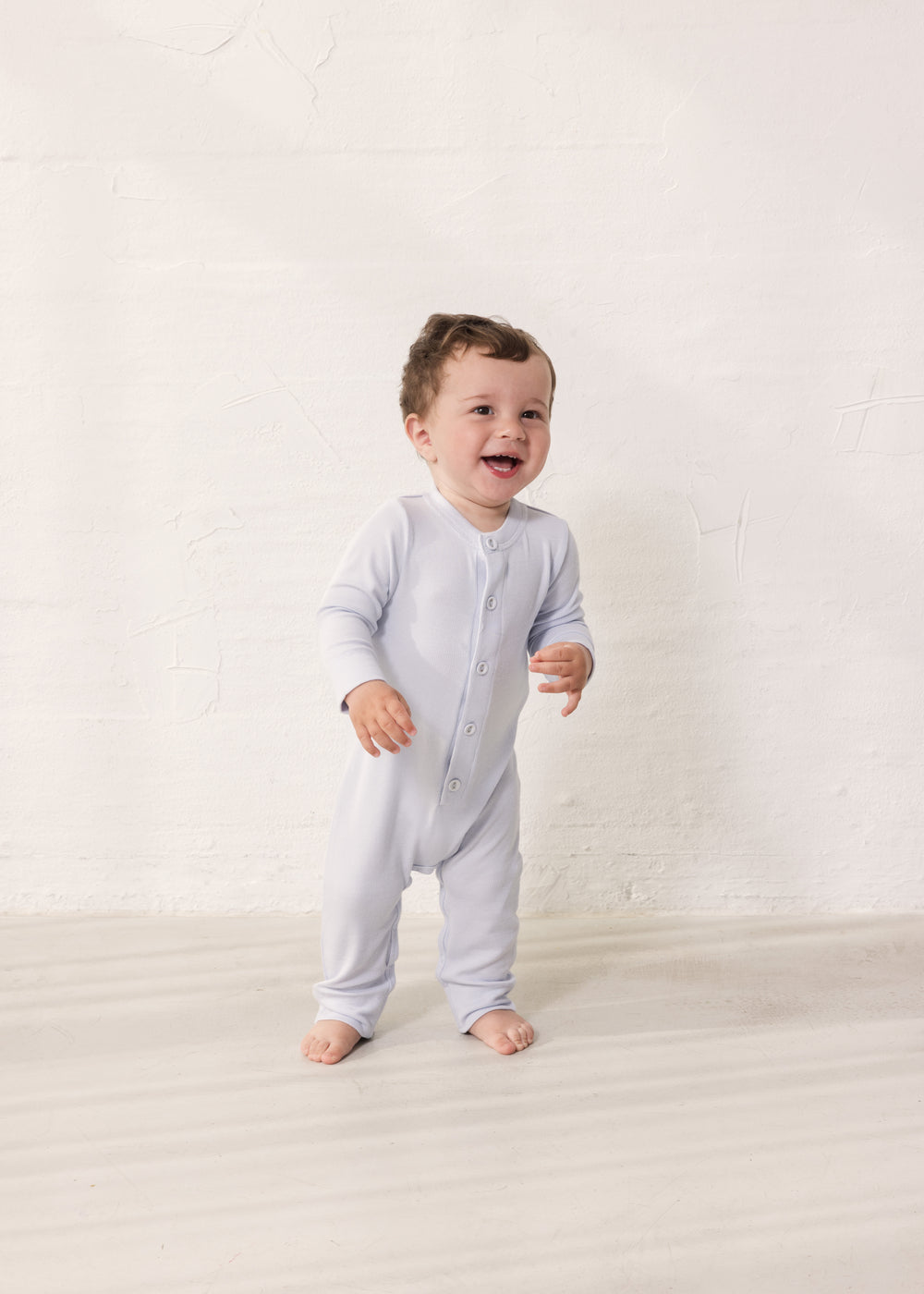 Baby iført Lysebå heldragt med en lang stolpe knaplukning