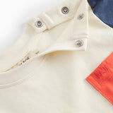 Kortærmet baby-T-shirt i råhvid med kontrastærmer og brystlomme