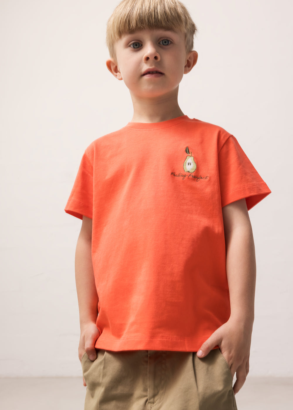 Barn iført orange T-shirt med lille motiv