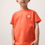 Barn iført orange T-shirt med lille motiv