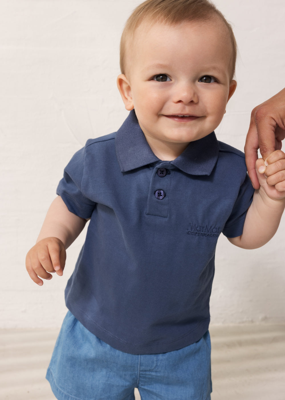 Baby iført Kortærmet blå polo t-shirt med krave og knaplukning