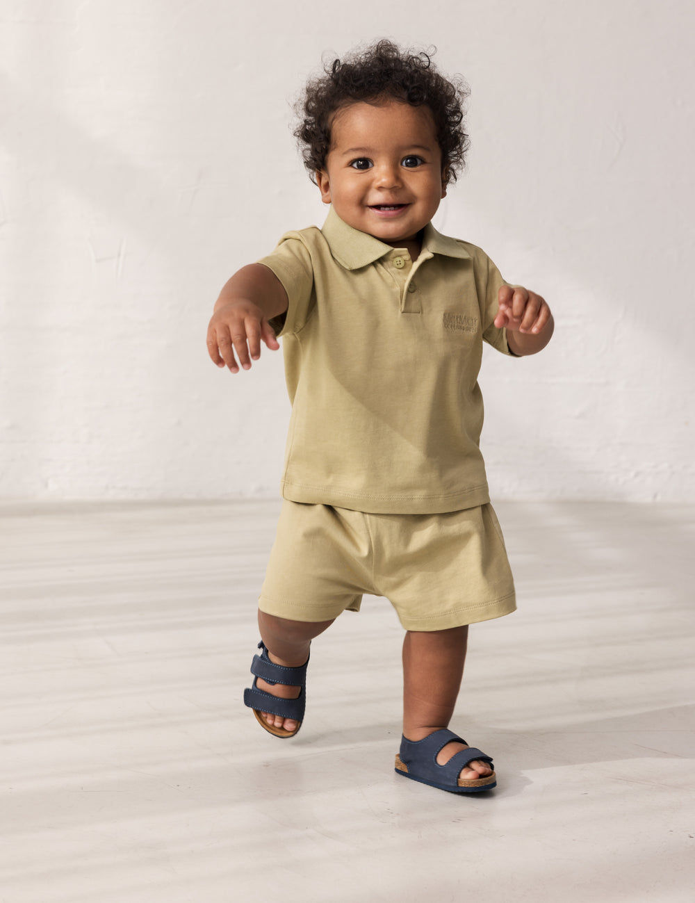 Baby iført kortærmet beige polo t-shirt med krave og knaplukning