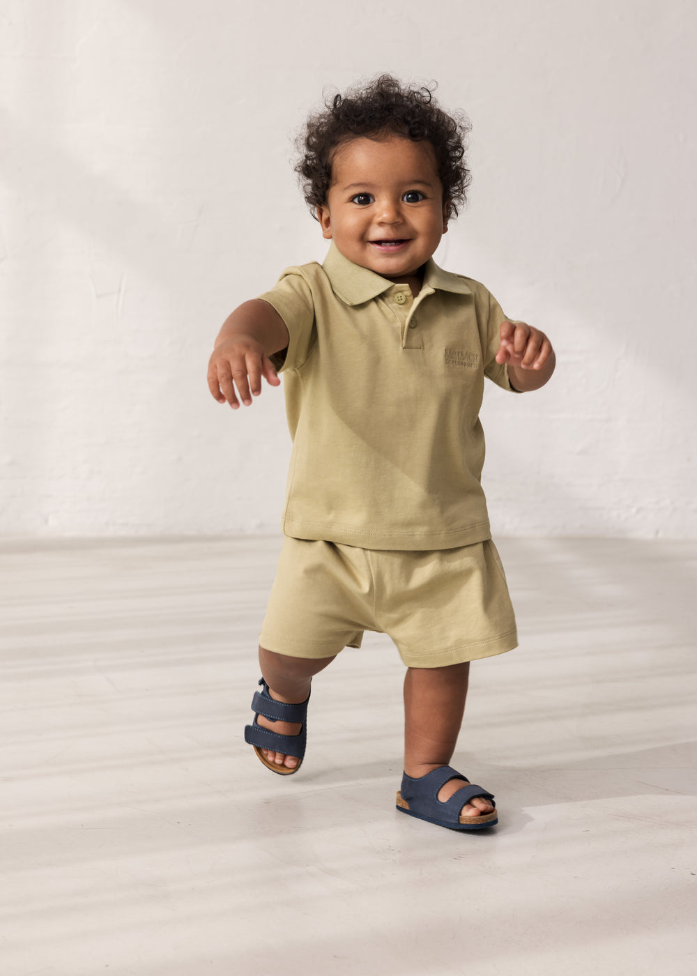 Baby iført kortærmet beige polo t-shirt med krave og knaplukning