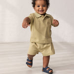 Baby iført kortærmet beige polo t-shirt med krave og knaplukning