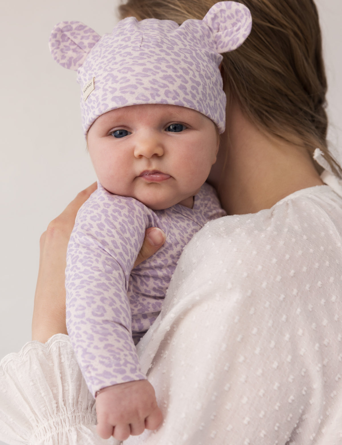 Baby iført lysellilla hue og bodystocking med leopardprint