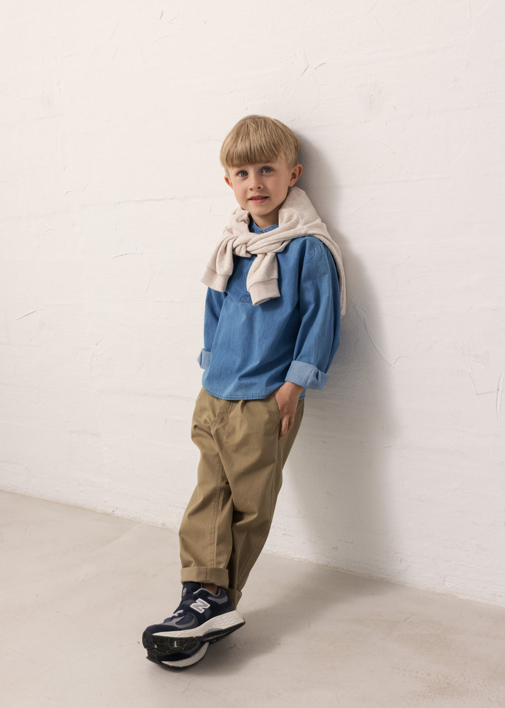 Barn iført blå denimskjorte og brune bukser
