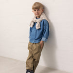 Barn iført blå denimskjorte og brune bukser