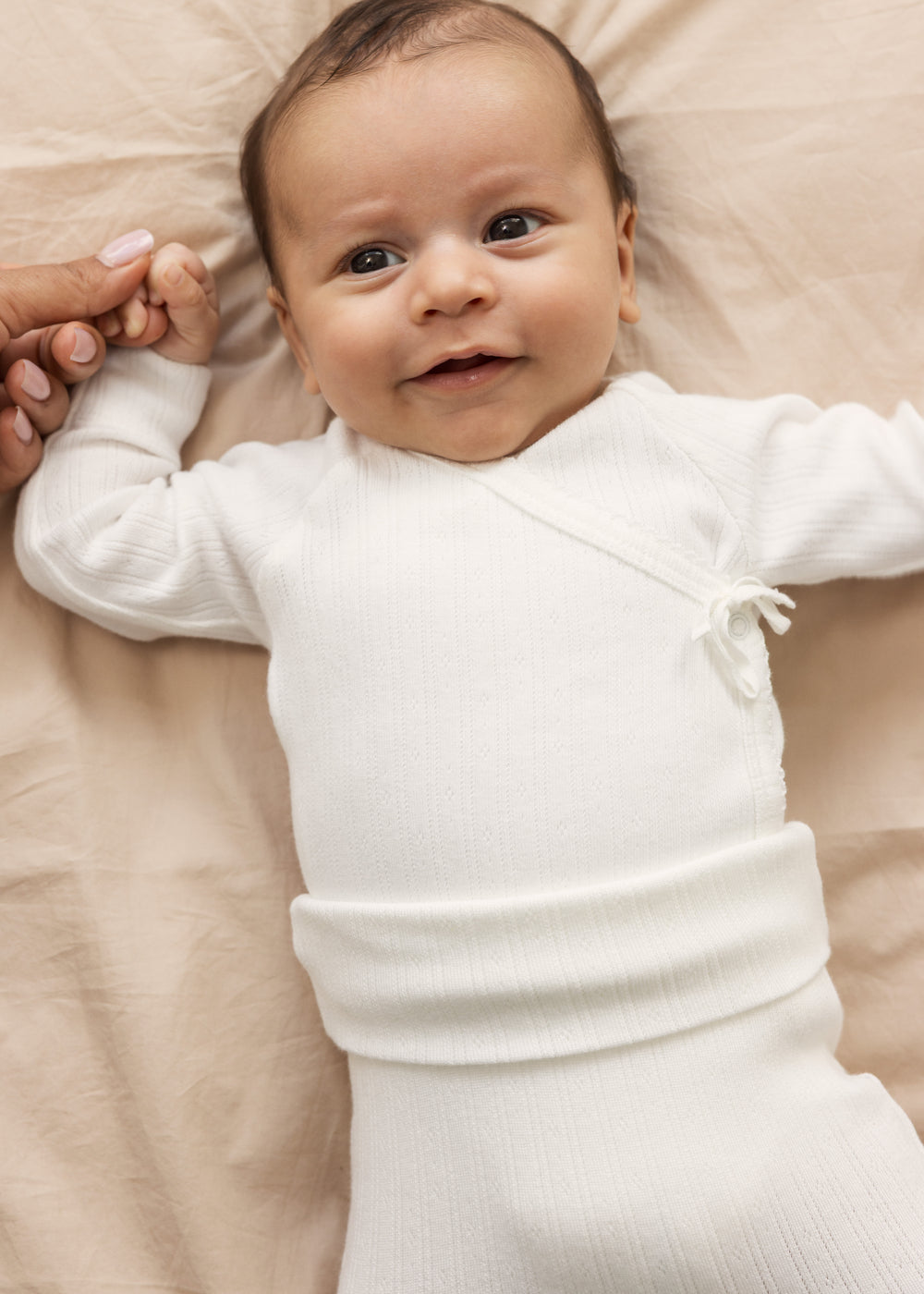 Baby iført råhvid body og bukser med elastisk talje
