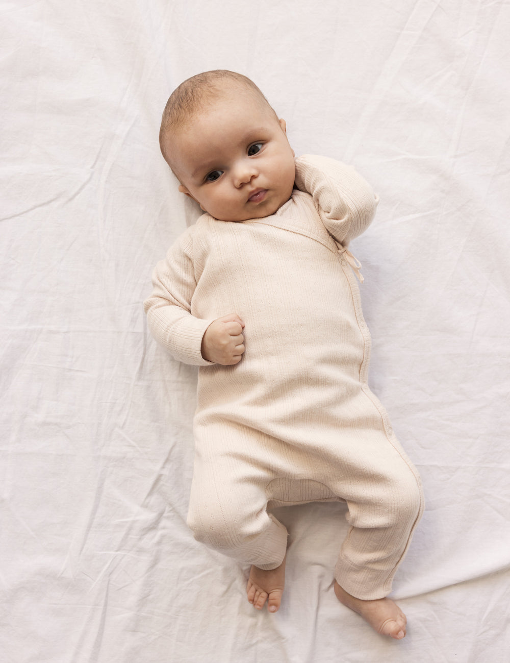 Baby iført lyserød langærmet pointelle heldragt med slå-om-lukning