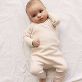 Baby iført lyserød langærmet pointelle heldragt med slå-om-lukning