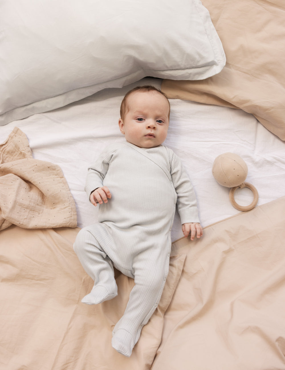 Baby iført langærmet lysegrøn pointelle heldragt med fødder