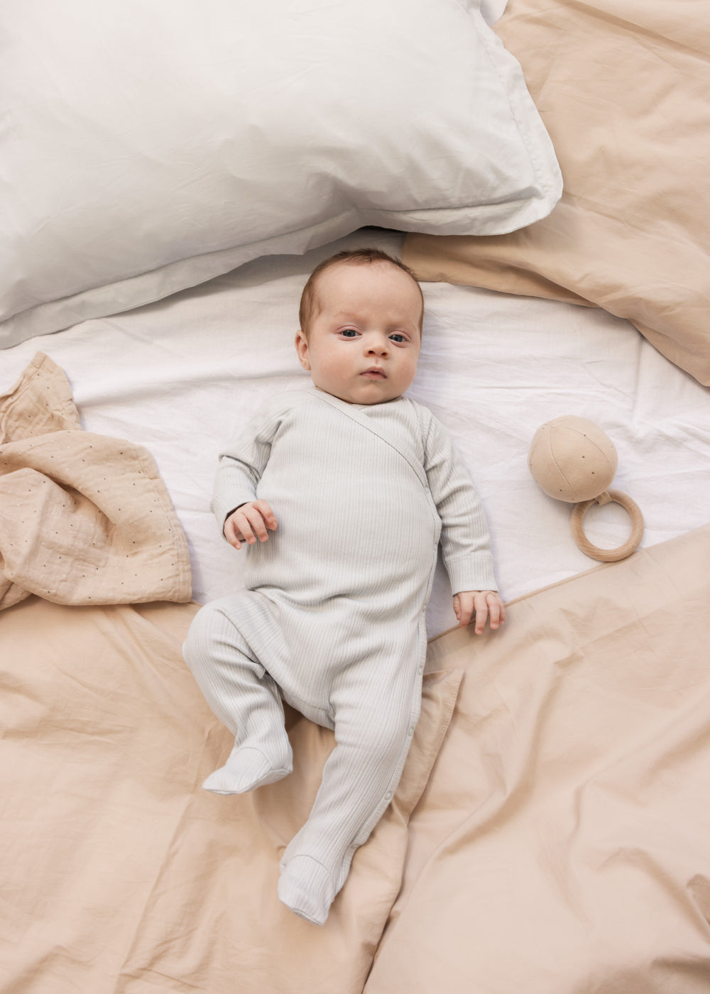 Baby iført langærmet lysegrøn pointelle heldragt med fødder