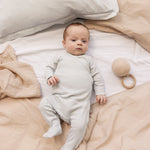 Baby iført langærmet lysegrøn pointelle heldragt med fødder