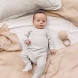 Baby iført langærmet lysegrøn pointelle heldragt med fødder