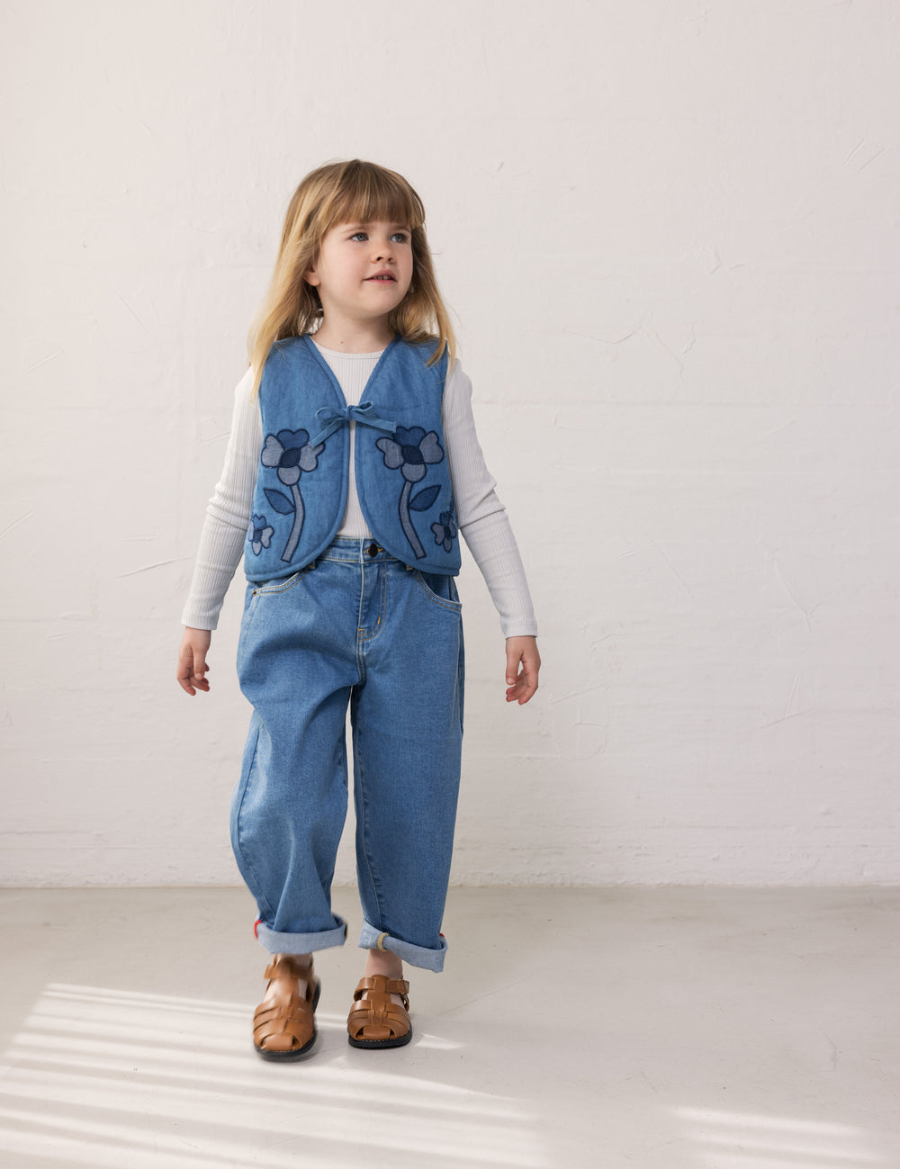 Barn iført blå denimvest med blomster og matchende bukser
