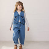 Barn iført blå denimvest med blomster og matchende bukser
