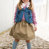 Barn iført denimvest sammen med kjole og solhat