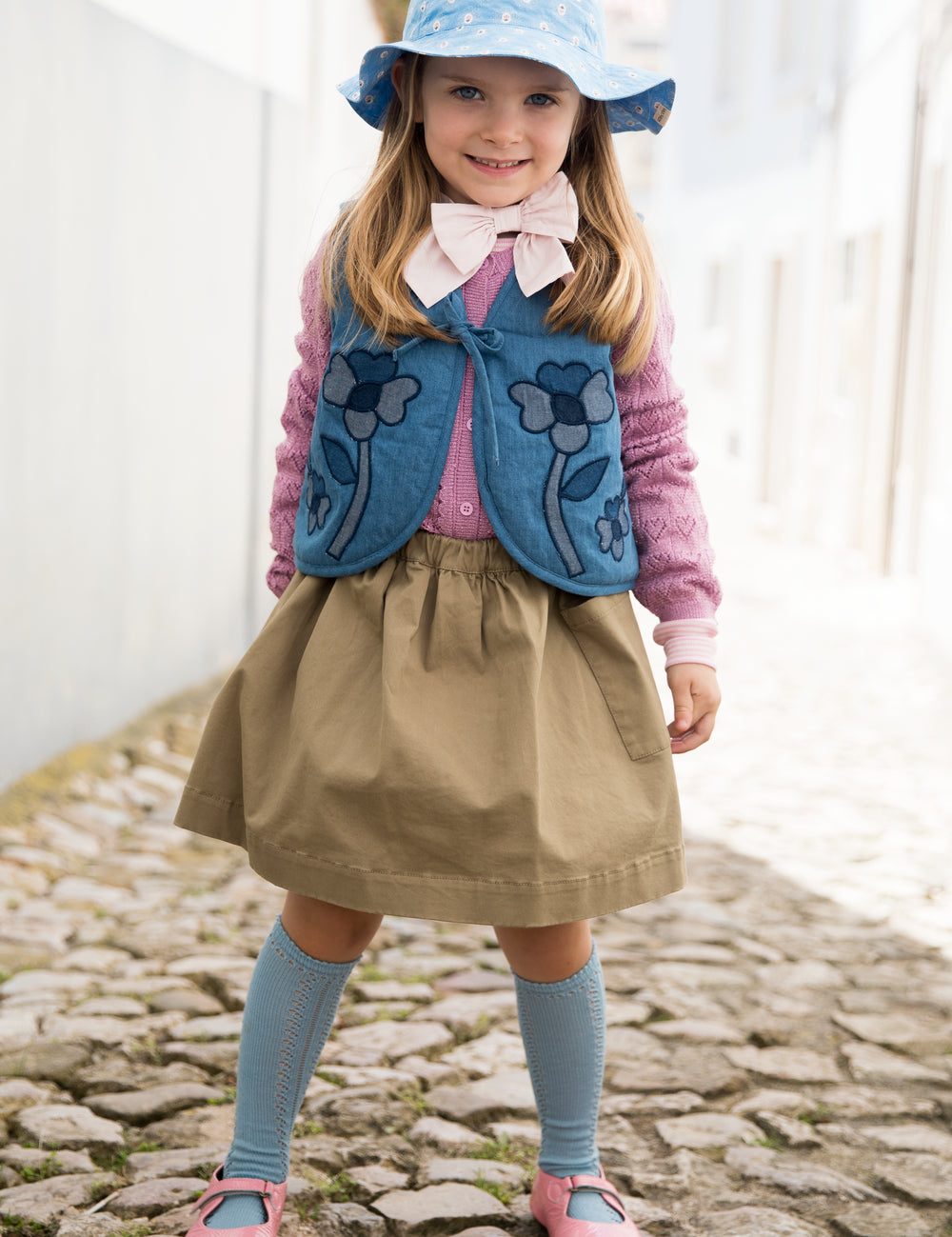 Barn iført blå solhat, vest og kjole