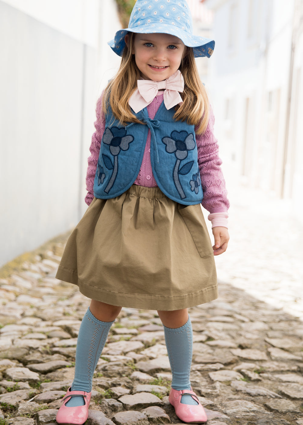 Barn iført blå solhat, vest og kjole