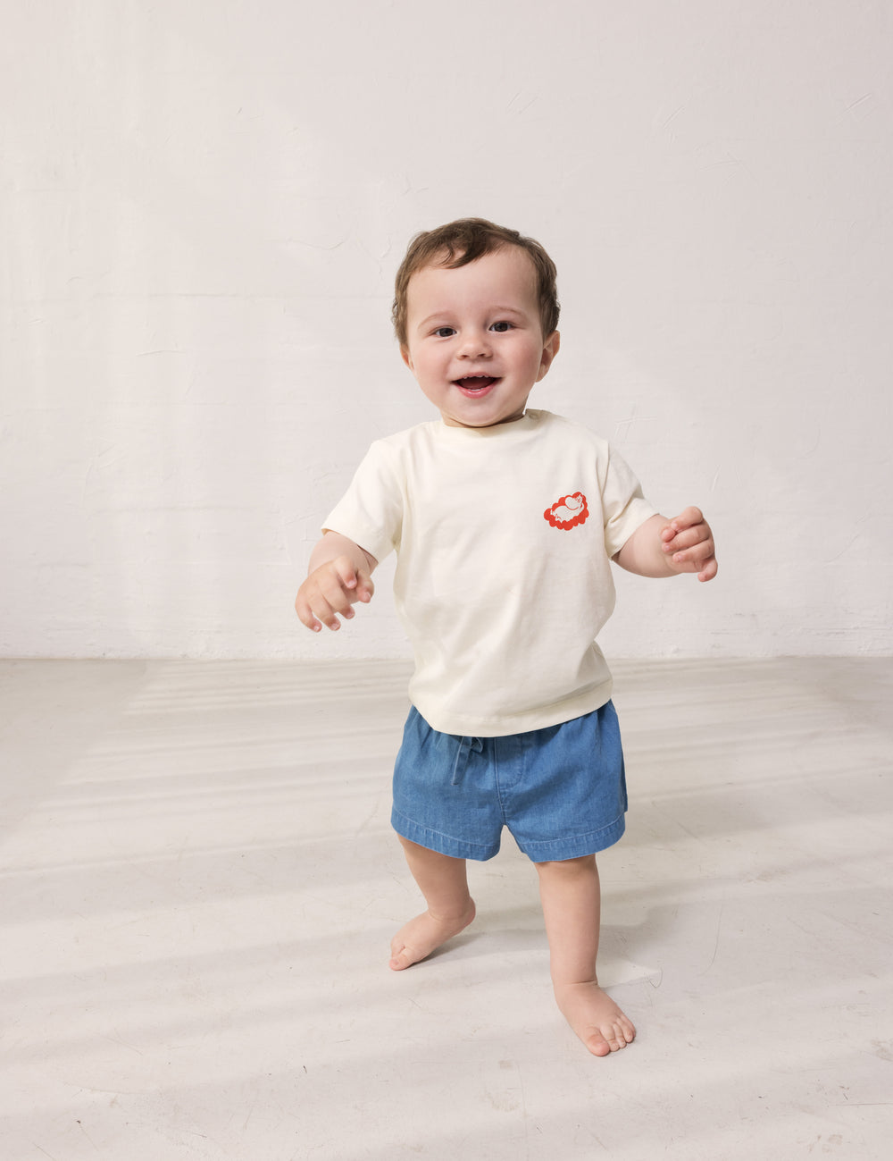 Baby iført T-shirt og blå denimshorts
