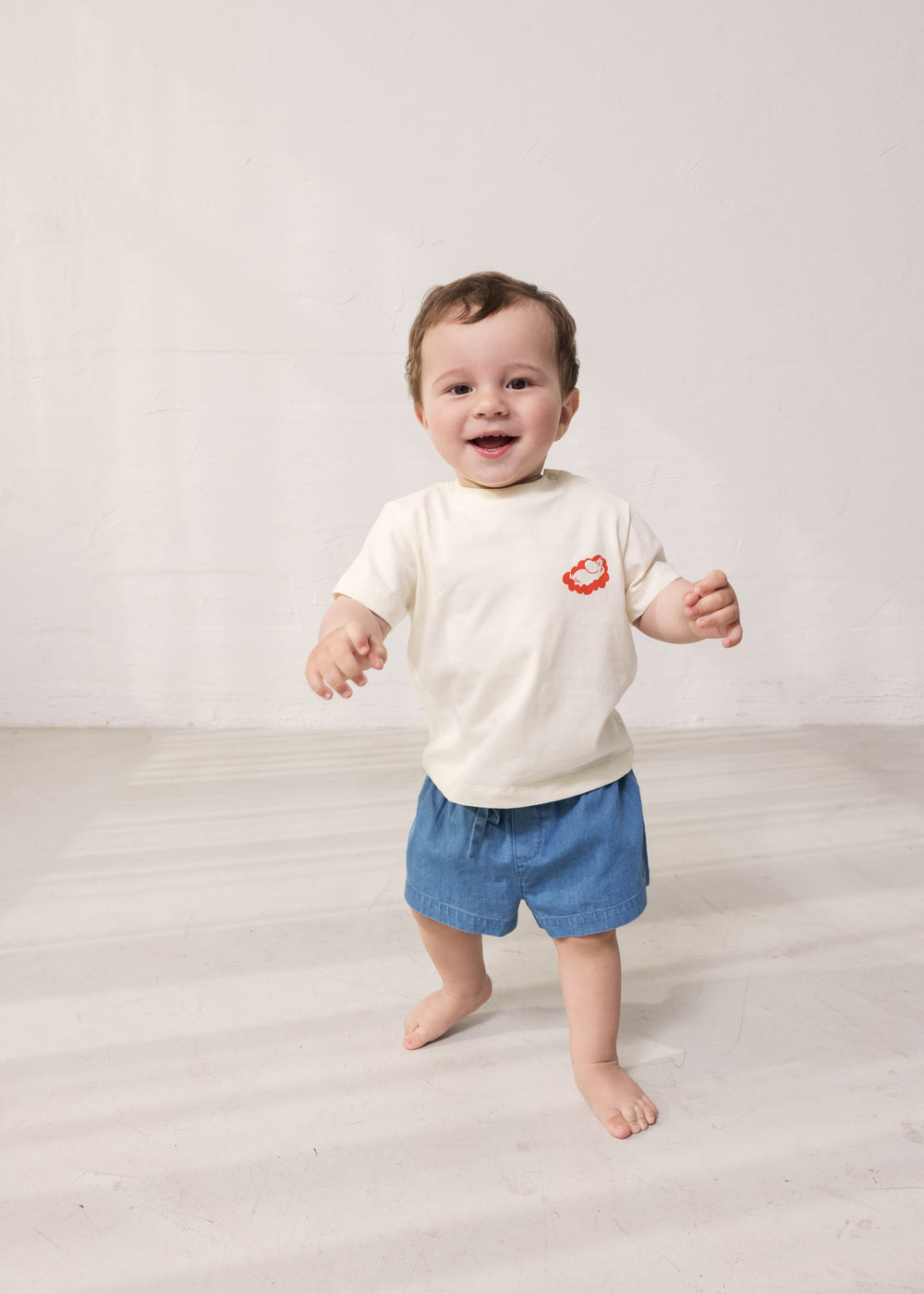 Baby iført T-shirt og blå denimshorts