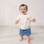 Baby iført T-shirt og blå denimshorts