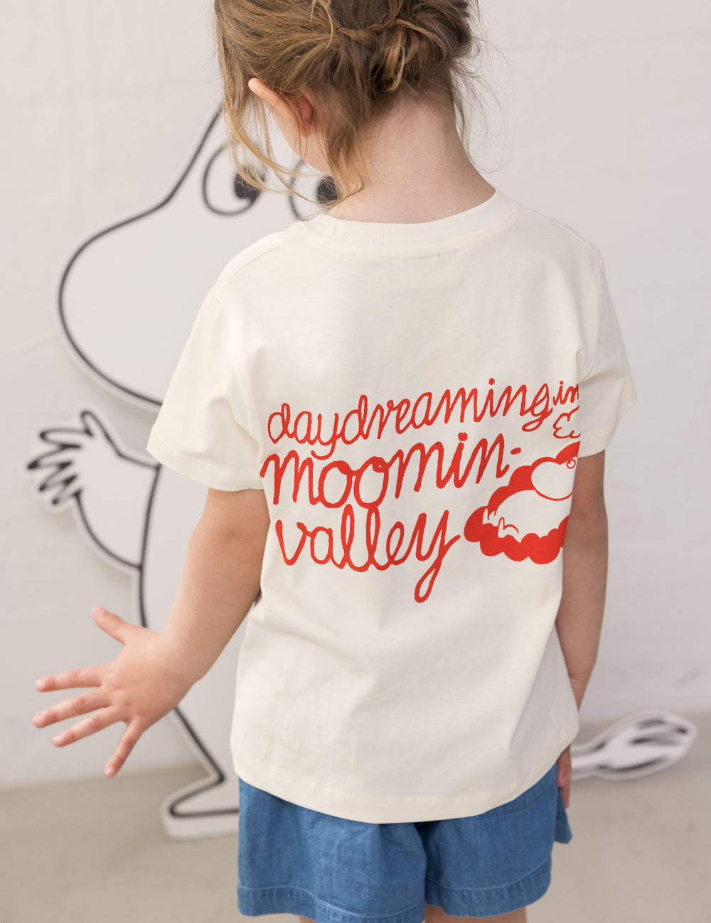 Barn iført Moomin T-shirt og blå denimshorts