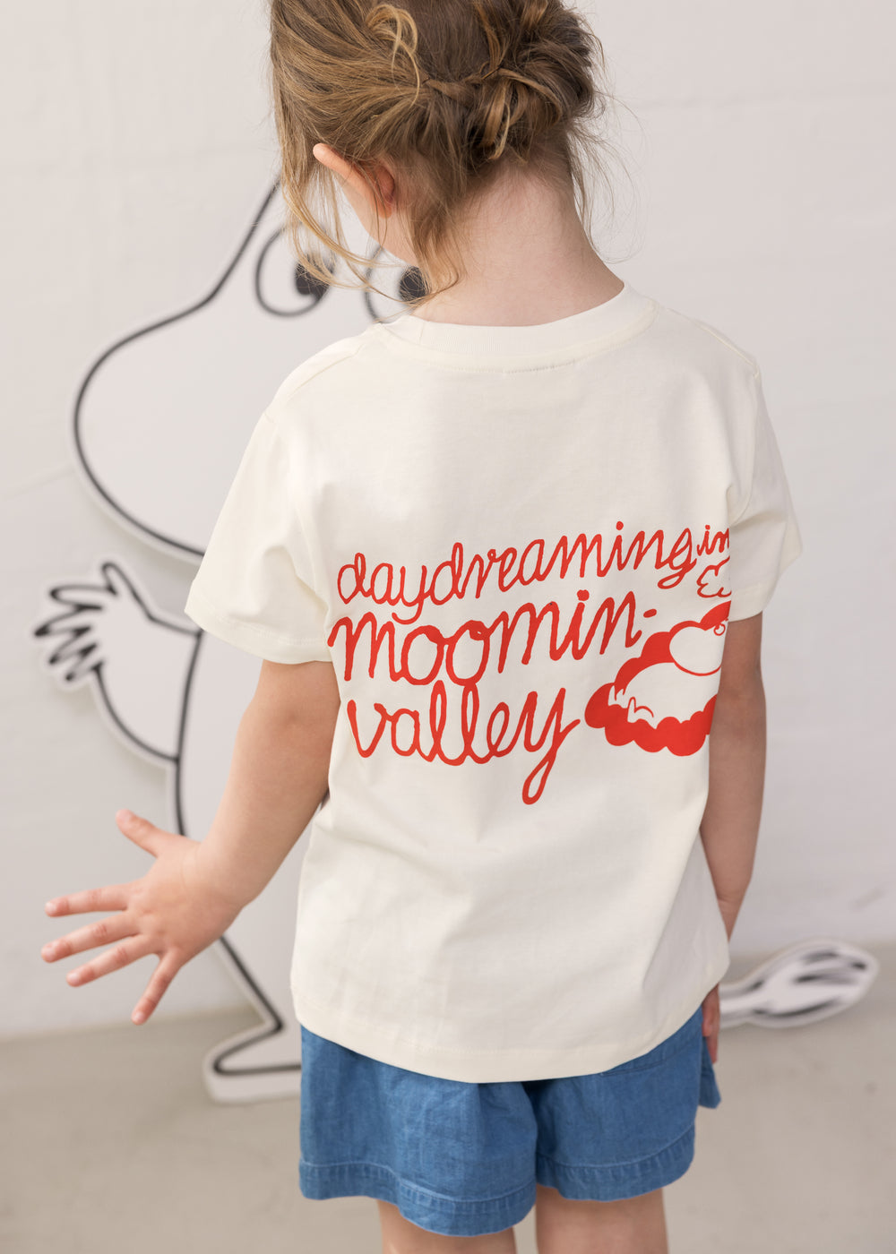 Barn iført Moomin T-shirt og blå denimshorts