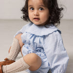 Baby pige iført lyseblå bodystocking med en fin bølget krave