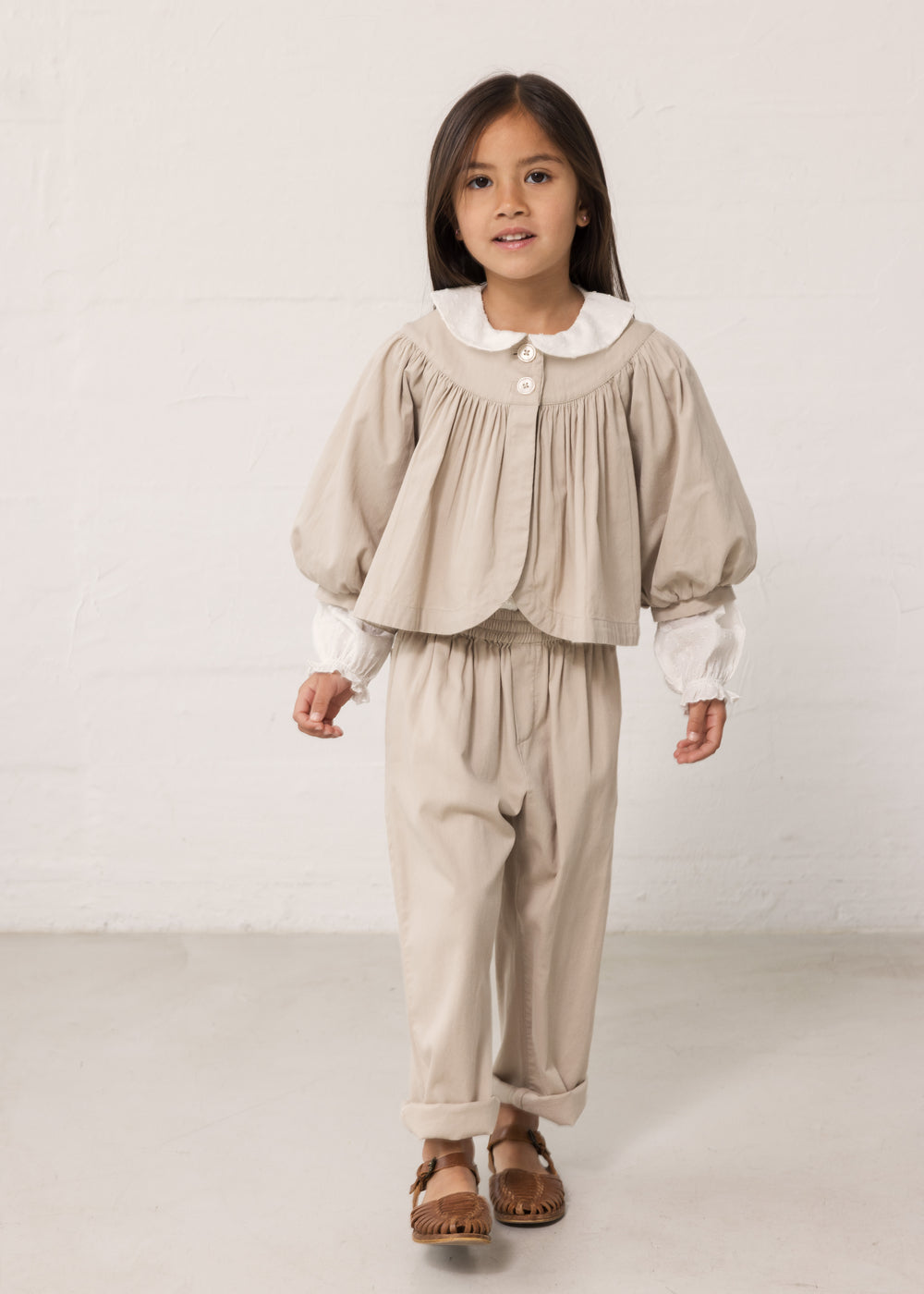 Barn iført lyst outfit med bukser og bluse