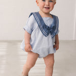 Bay iført kortærmet heldragt med matroskrave og dekorativ sløjfe