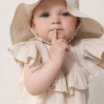 Baby iført beige sommerhat og matchende kjole