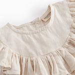 Ærmeløs beige top til baby med flæsedetaljer