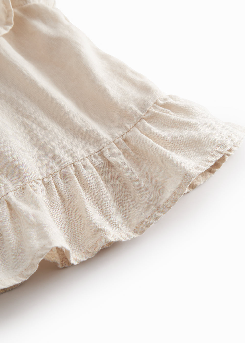 Ærmeløs beige top til baby med flæsedetaljer