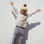 Barn iført beige skjorte og ternet bukser 
